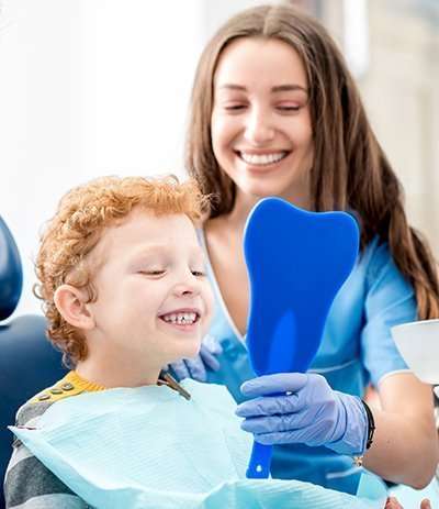 child with dentist looking into mirror